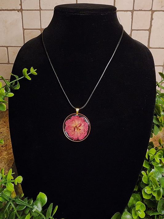 Round necklace featuring flower hanged on a black cord