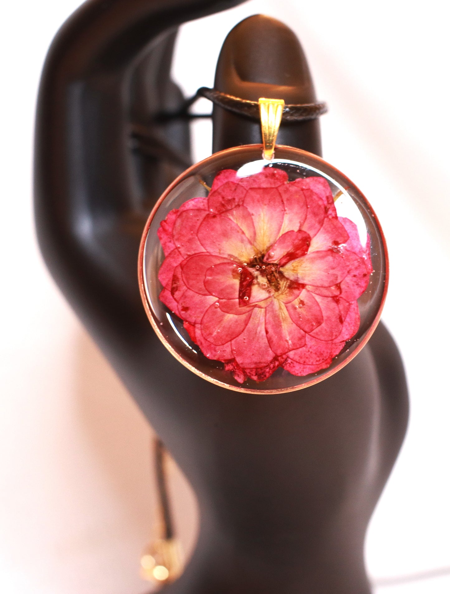 Round necklace featuring flower hanged on a black cord