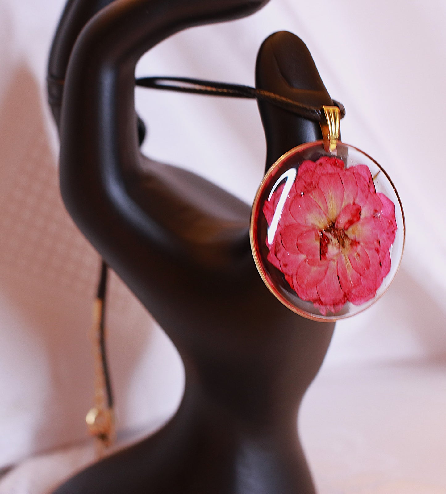 Round necklace featuring flower hanged on a black cord